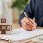 Una persona firma un documento de compraventa de una casa
